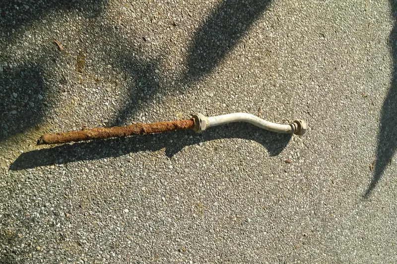 An old, corroded lead gooseneck pipe that once connected a house to the water main